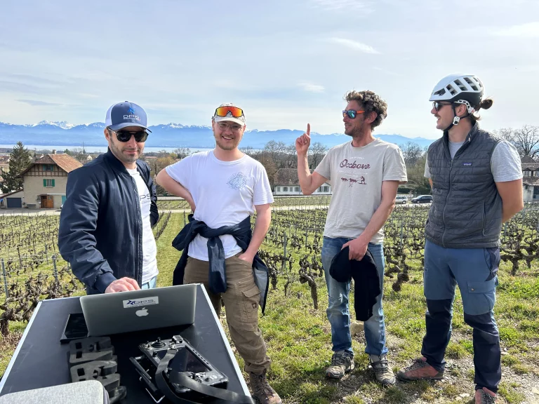 4 hommes devant un ordinateur dans un vignoble suisse avec le lac léman en fond